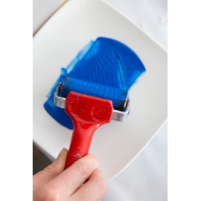 Rolo de pintura com pega vermelha a aplicar tinta azul.