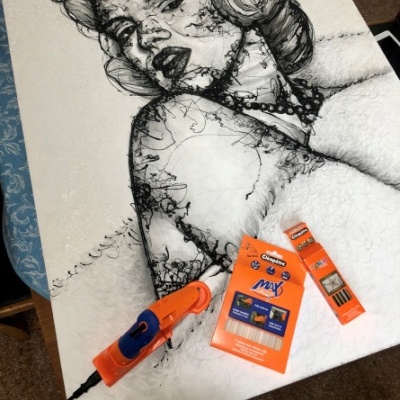 Quadro com retrato desenhado em linhas pretas, ferramenta elétrica e embalagens laranjas sobre uma tela branca