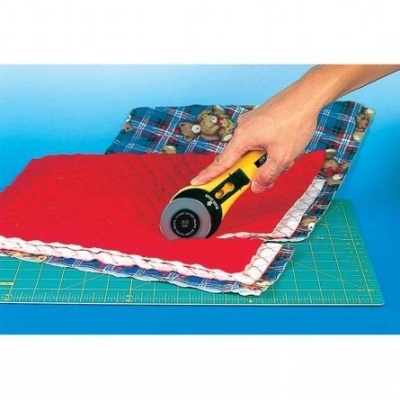 Roda de corte para tecido a cortar tecido vermelho sobre tapete de corte verde