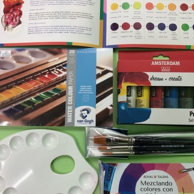 Conjunto de materiais e livros para pintura acrílica sobre fundo verde