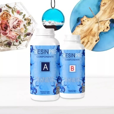 Frascos de resina transparente RESIN PRO com rótulos azuis componentes A e B, rodeados por objetos artísticos em resina