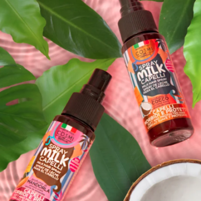 Dois frascos coloridos de spray capilar sobre folhas verdes e fundo rosa com um meio coco