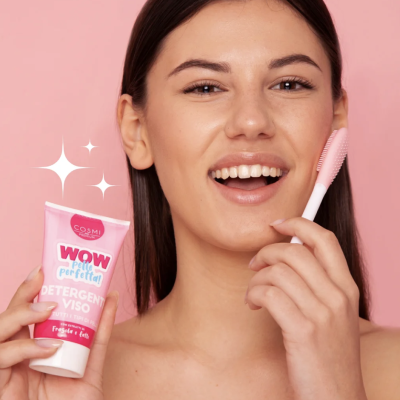 Mulher segura detergente facial rosa e escova de limpeza facial cor-de-rosa