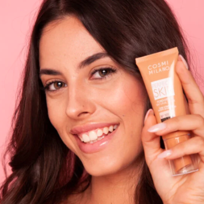 Mulher segurando tubo de creme COSMI MILANO em fundo rosa