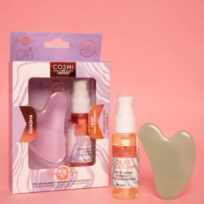 Conjunto de cosméticos com gua sha e óleo corporal em fundo rosa