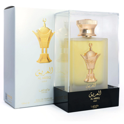 Frasco de perfume dourado dentro de caixa transparente e embalagem branca ao lado.