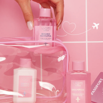 Produtos COSMI PREMIUM para banho e cuidado corporal em garrafas rosa e branco, com embalagem transparente e passaporte rosa no fundo