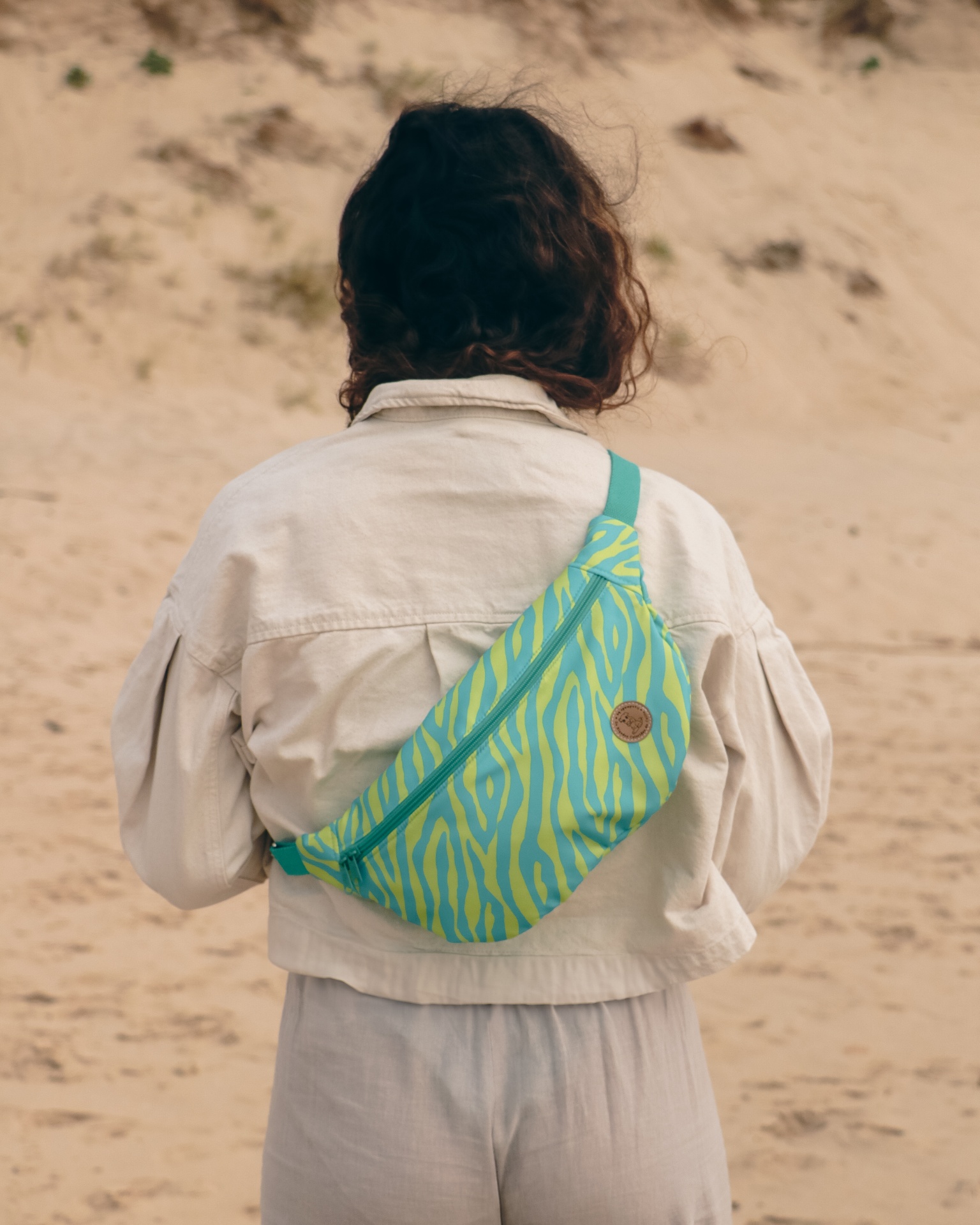 Pochete verde com padrão amarelo zebrado na praia