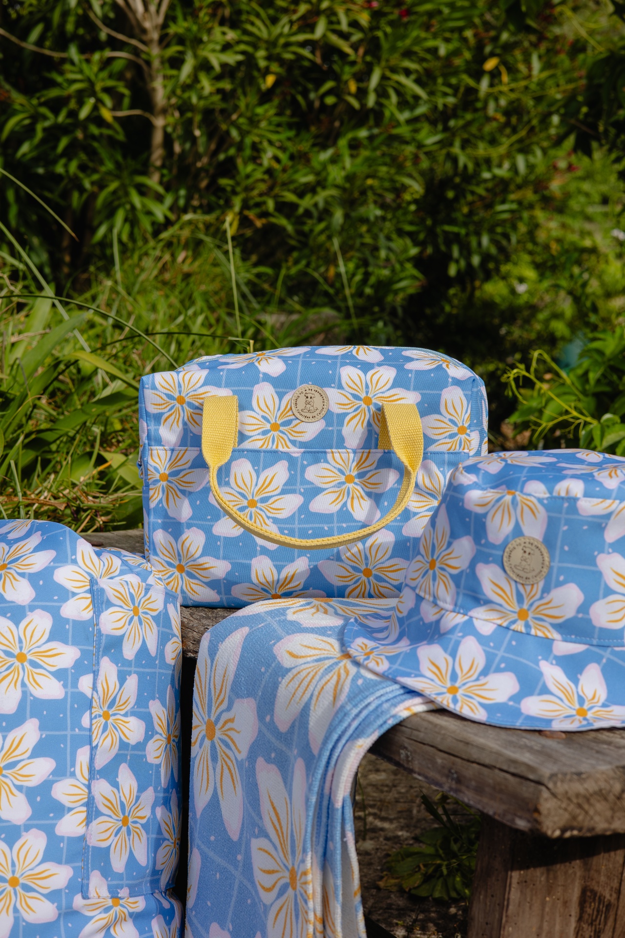 Conjunto de bolsa, chapéu e toalha com padrão floral azul e amarelo ao ar livre