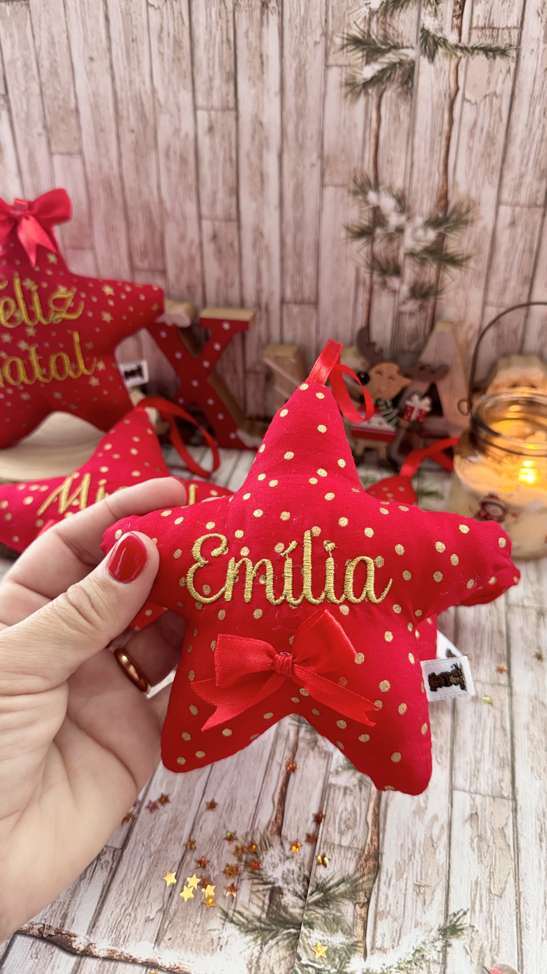 Estrela de tecido vermelha com bordado Emília e decorada ao fundo com elementos natalícios