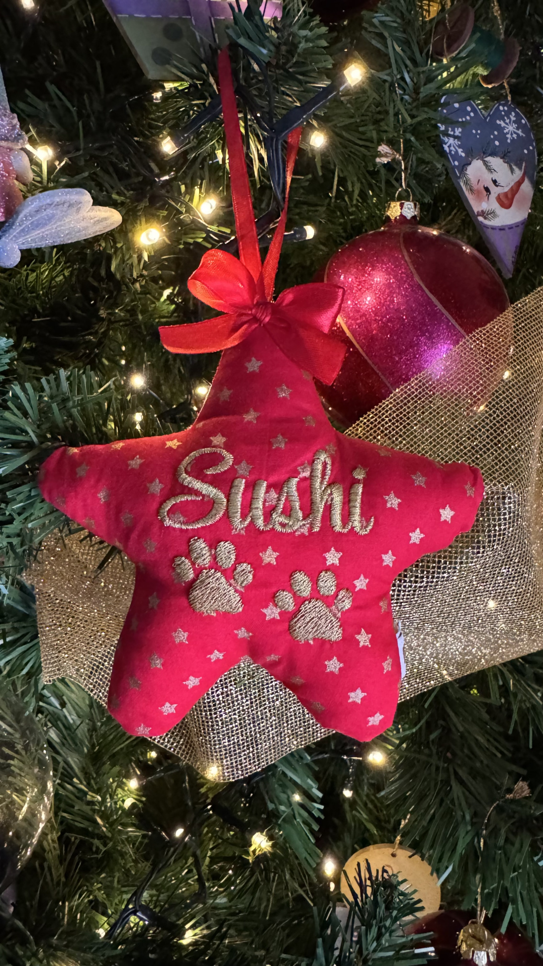 Enfeite de Natal vermelha em forma de estrela com o nome Sushi bordado e patas em tecido na árvore de Natal