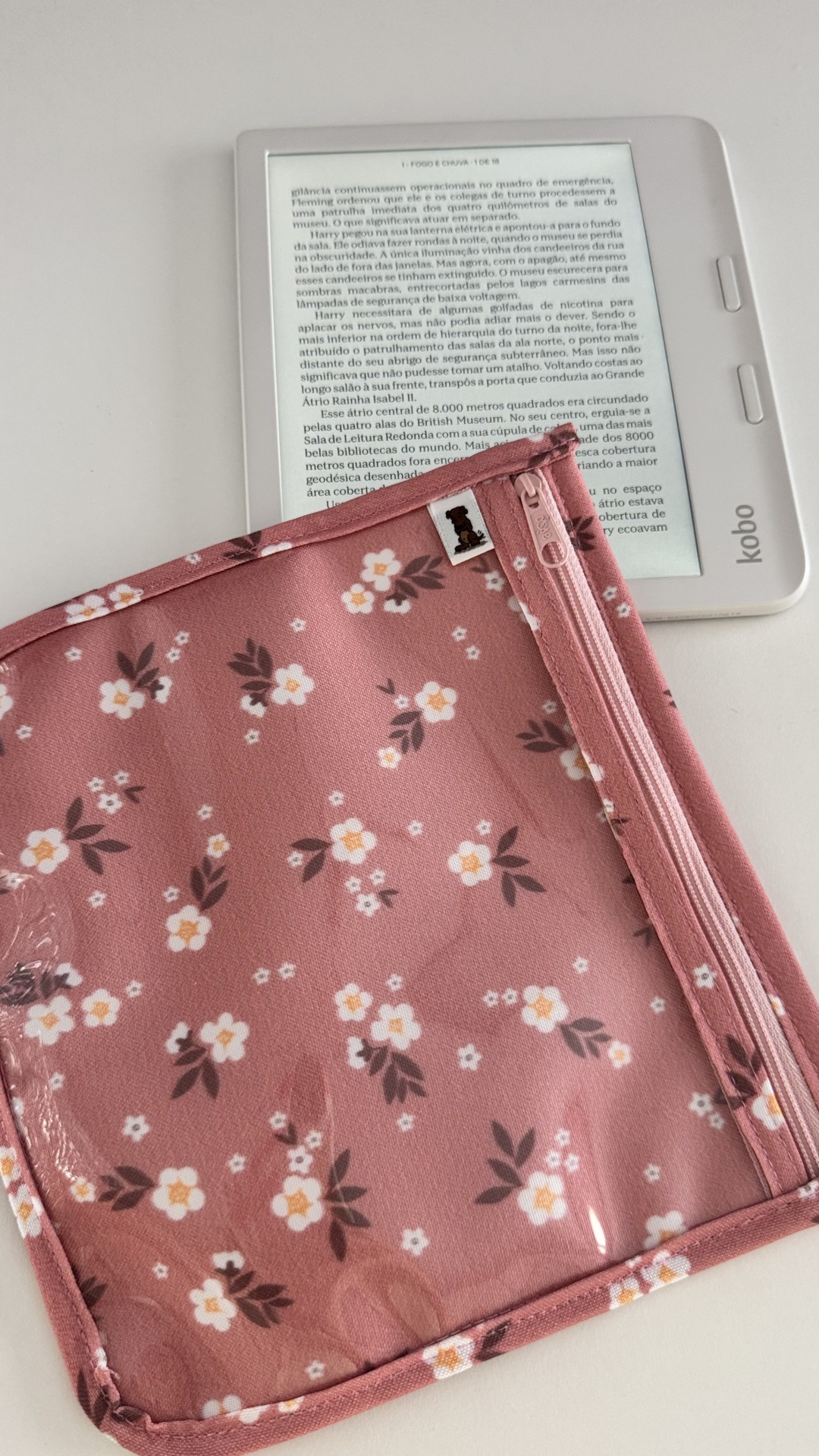 Capa rosa com flores brancas e amarelas sobre leitor Kobo branco com texto em português
