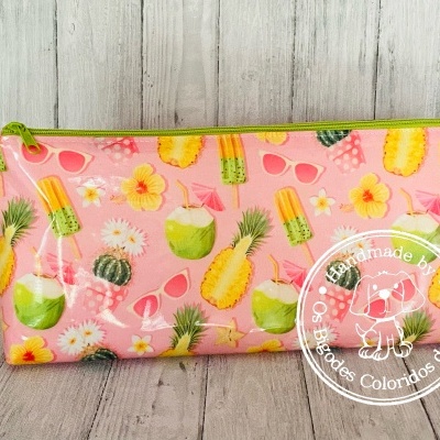 Estojo retangular com padrão colorido de frutas tropicais e óculos em fundo rosa.
