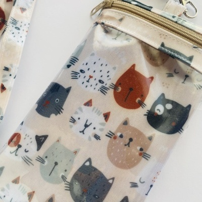 Bolsa pequena de tecido com padrão de gatos coloridos e fecho dourado.