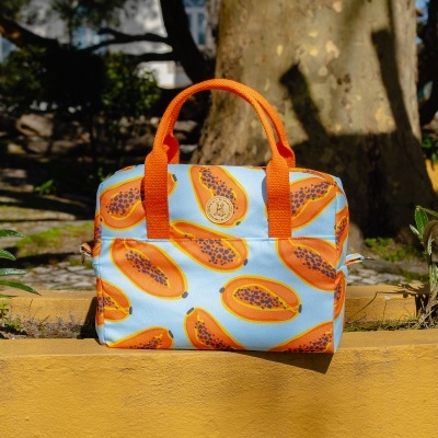 Mala azul com padrão de papaias e alças laranja num ambiente exterior