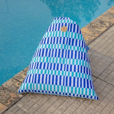 Saco de almofada com padrão de riscas azul, branco e verde ao lado de uma piscina.