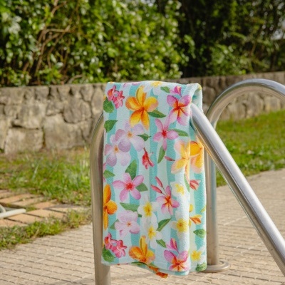 Toalha de tecido floral colorida pendurada em estrutura metálica ao ar livre