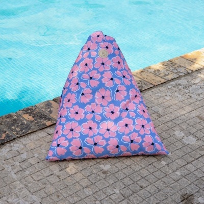 Almofada grande triangular azul com flores rosa junto a piscina