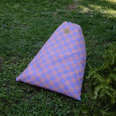 Bean bag lilás e rosa em padrão xadrez na relva com etiqueta redonda de pele