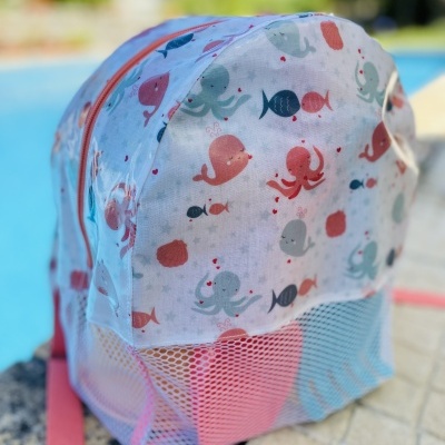 Mochila infantil branco com padrão de animais marinhos junto a piscina