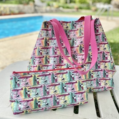 Mala e bolsa pequenas com padrão de Snoopy surfista com alças cor-de-rosa junto a piscina