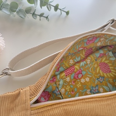 Mala de veludo cotelê castanho claro com interior floral e tira ajustável