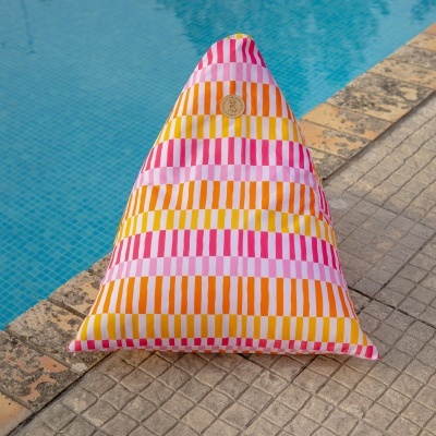 Almofada colorida com riscas verticais perto de uma piscina