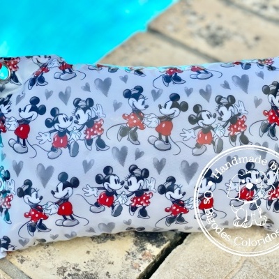 Almofada retangular com padrão de Mickey em fundo cinza azul claro junto a piscina