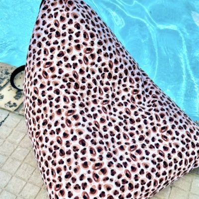 Pufe triangular com padrão de estampa animal junto a uma piscina