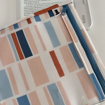 Capa protetora geométrica com fecho de correr azul enviada sobre um leitor Kobo branco com texto visível no ecrã.