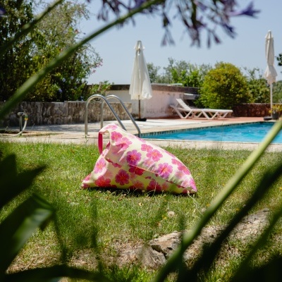 Almofada triangular floral junto a uma piscina e espreguiçadeiras exteriores