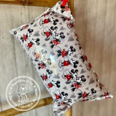 Almofada decorativa estampada com personagens de desenho animado, pendurada em estrutura de madeira.
