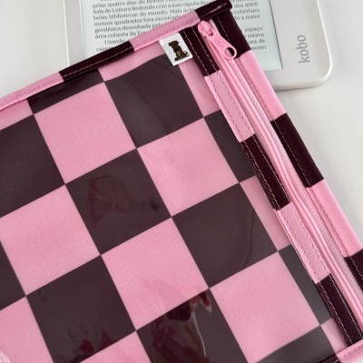 Leitor digital Kobo branco com texto em português e capa rosa castanha xadrez com fecho e símbolo de urso