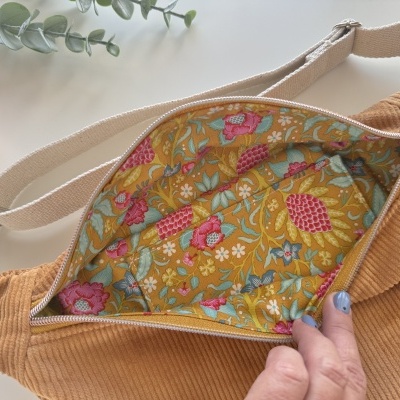 Bolsa tiracolo bege com padrão floral interior em tecido e alça ajustável