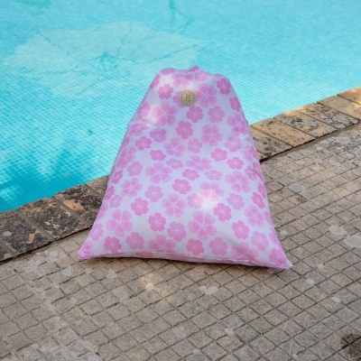pufe triangular rosa com padrão de flores perto de piscina