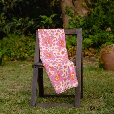 Toalha floral cor de rosa pendurada numa cadeira de madeira exterior.