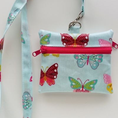 Bolsa pequena azul claro com borboletas coloridas e fecho rosa
