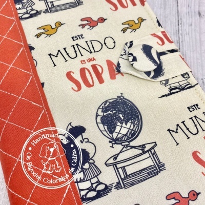 Tecido com padrão infantil e texto em castelhano ao lado de tecido vermelho com padrão branco