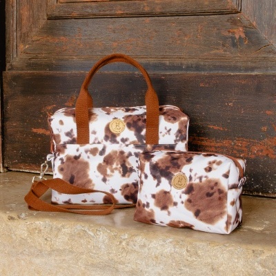Conjunto de duas bolsas castanhas e brancas com padrão manchado, alças castanhas, num degrau de pedra e porta de madeira