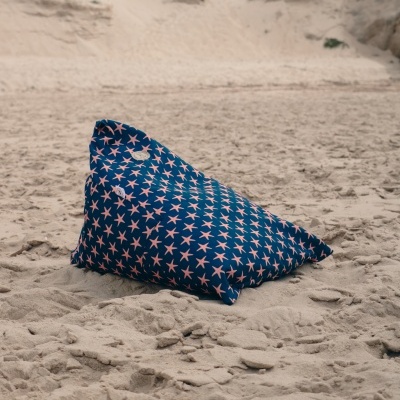 Pufe triangular azul com padrão de estrelas-do-mar cor-de-rosa na areia