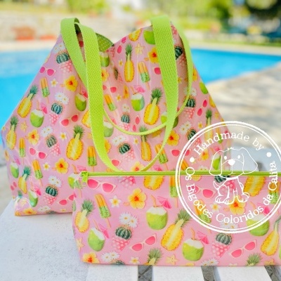 Conjunto de bolsa rosa com padrão de frutas tropicais e flores e carteira, alças verdes, selo branco, ao ar livre junto a piscina