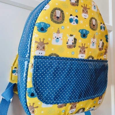 Mochila infantil amarela com animais e bolso azul de pontos brancos
