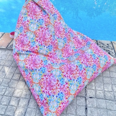 Puff triangular floral colorido ao lado de piscina