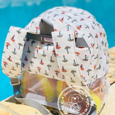 Mochila branca com padrões de veleiros coloridos junto a piscina