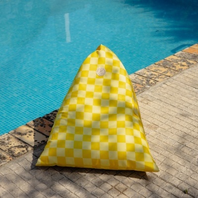 Pufe triangular amarelo e branco ao lado da piscina