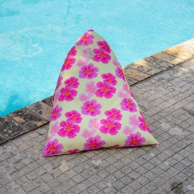 Pufe triangular amarelo com flores cor-de-rosa ao lado de uma piscina