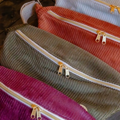 Cinco bolsas coloridas com fechos dourados sobre fundo de madeira.