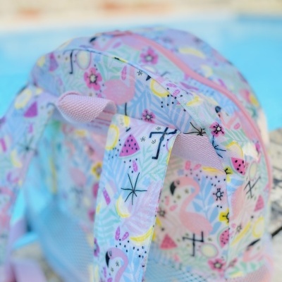 mochila colorida com padrão de flamingos e melancia junto a piscina