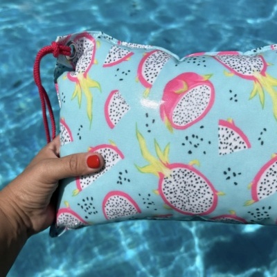 Mala azul claro com padrão de pitaya colorida com cordão vermelho junto a piscina