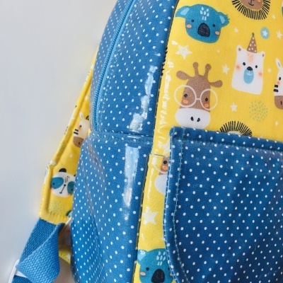 Mochila infantil azul e amarelo com padrão de animais e bolinhas